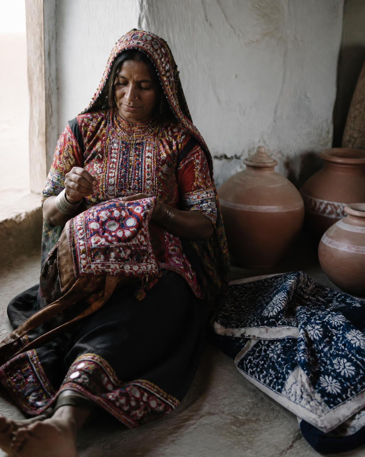 A Kutchi craftswoman embroidering a mirror-work panel in a whitewashed mud hut